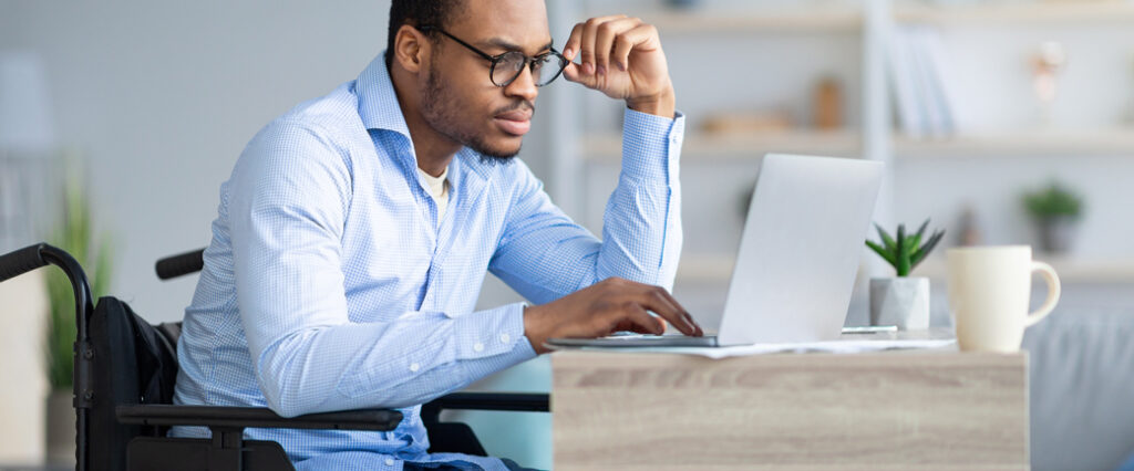 A man at a computer adjusts his glasses