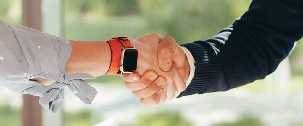 Two people shake hands in an office