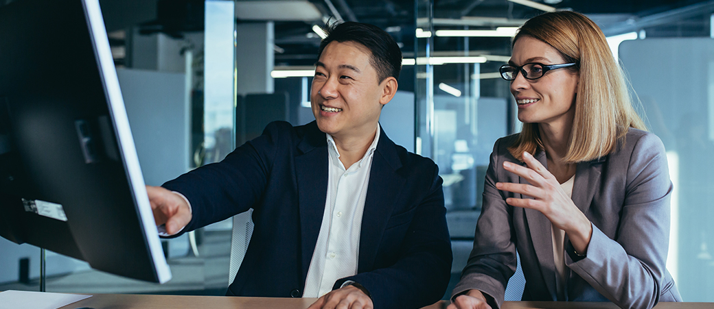 Two colleagues review adobe customer journey analytics data on computer screen