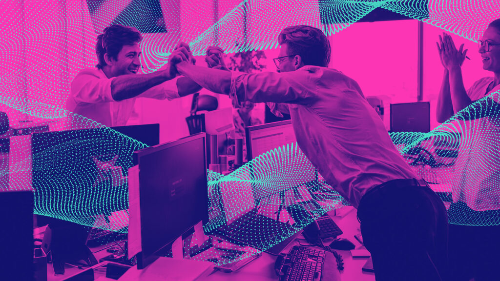Three colleagues celebrate teamwork in an office setting