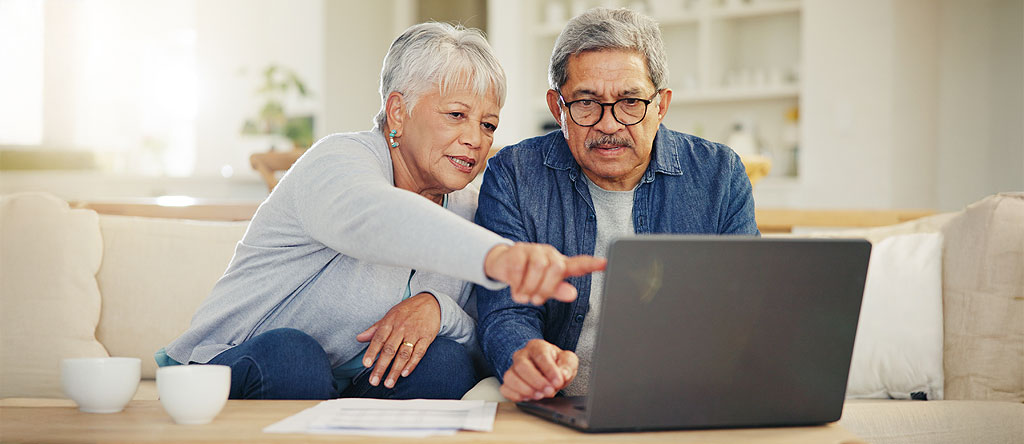 Elderly couple trying to figure out user experience on a laptop in their living room.
