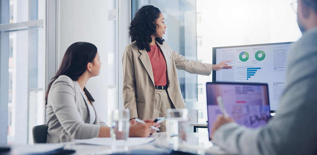 Consultant displaying analytics dashboard in a meeting with colleagues