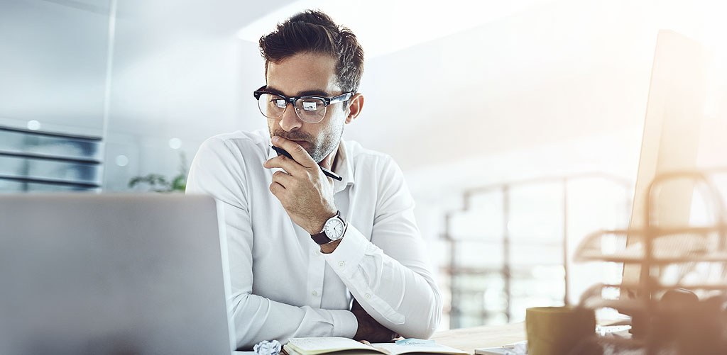 Marketing professional looking skeptically at laptop screen, illustrating uncertainty of data distrust