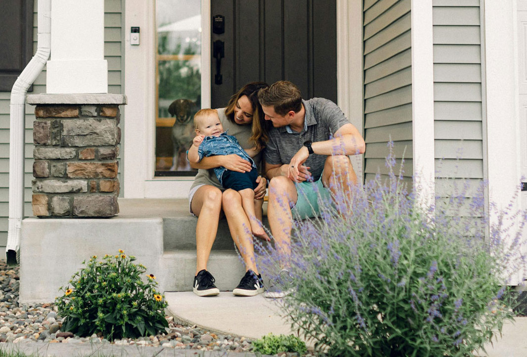 Bozzuto client story thumbnail of a family sitting on their porch of their home