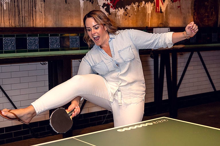 Kim Stevenson playing table tennis to represent core value "Fun"