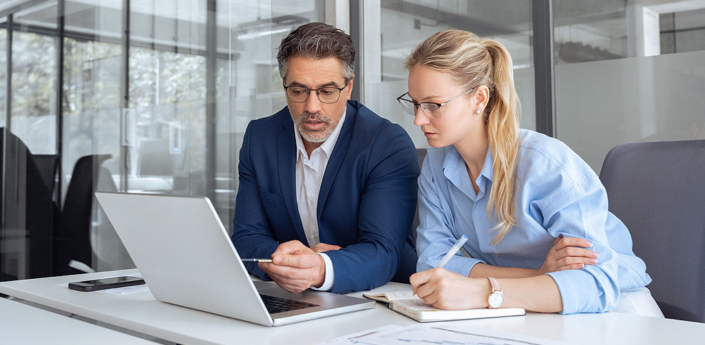 A man points to a laptop screen while a female colleague takes notes at a desk to represent data distrust in customer behavior data